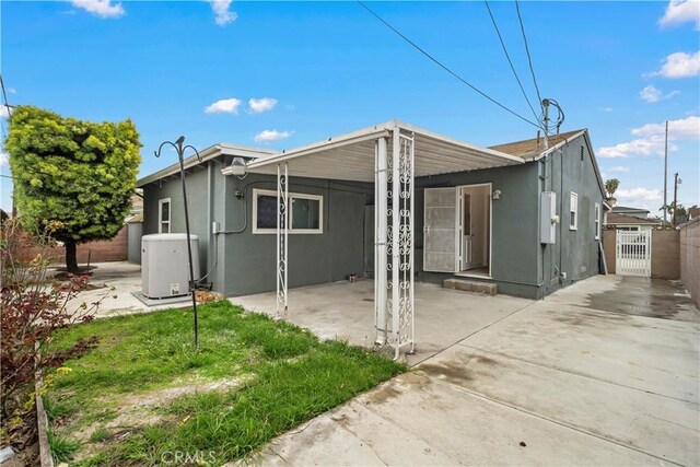 back of property featuring a carport, fence, a patio, and stucco siding