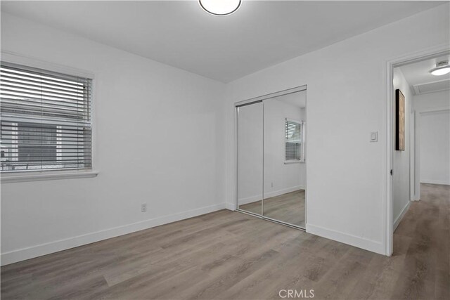 unfurnished bedroom with a closet, wood finished floors, and baseboards