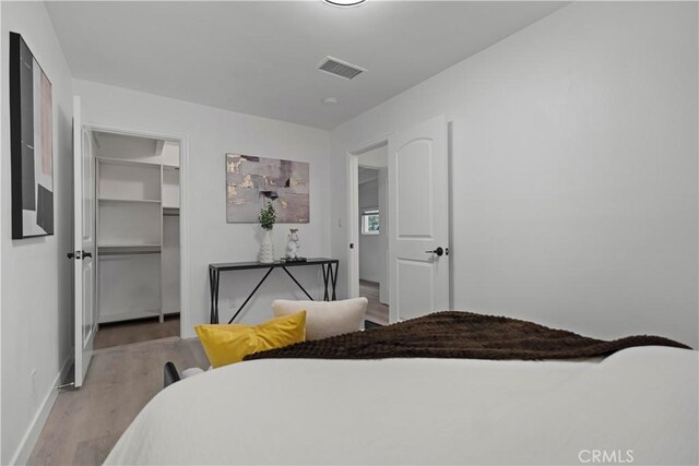 bedroom featuring a closet, visible vents, baseboards, and wood finished floors