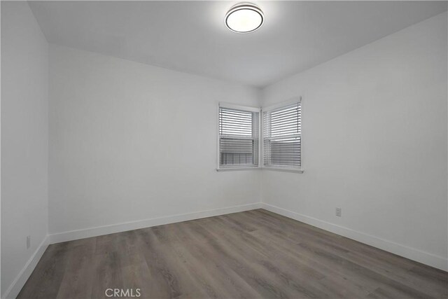 unfurnished room with baseboards and wood finished floors