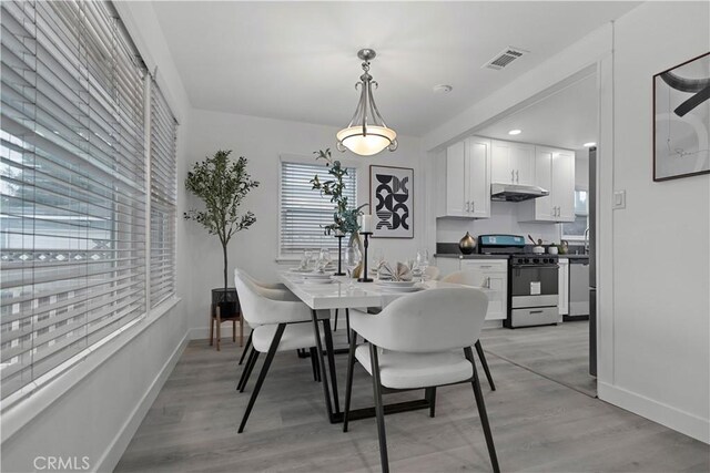 dining room featuring visible vents, light wood-style flooring, and baseboards