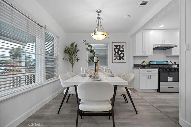 dining area featuring light wood-type flooring, visible vents, and baseboards