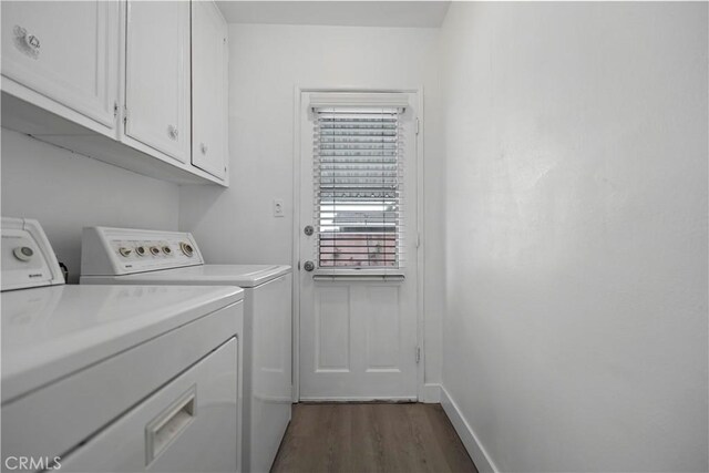 clothes washing area featuring dark wood-style flooring, cabinet space, baseboards, and washing machine and clothes dryer