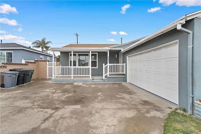 ranch-style home featuring concrete driveway, a porch, fence, and stucco siding