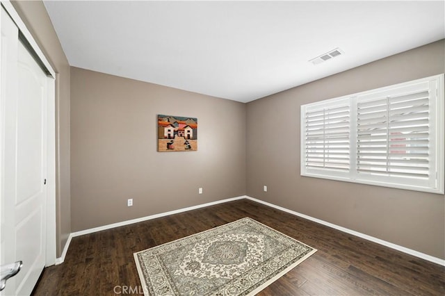 bedroom with a closet, visible vents, baseboards, and wood finished floors