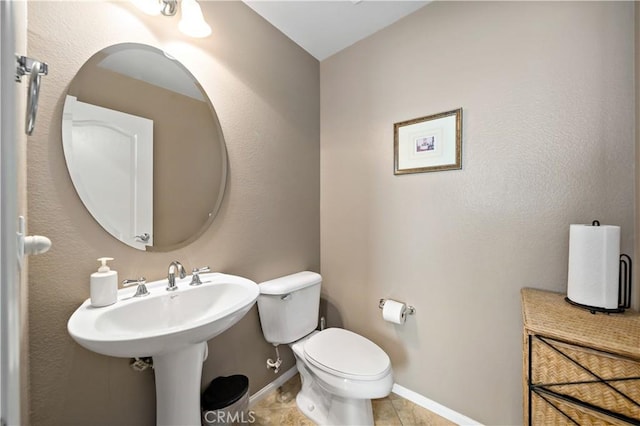 bathroom with tile patterned flooring, baseboards, and toilet