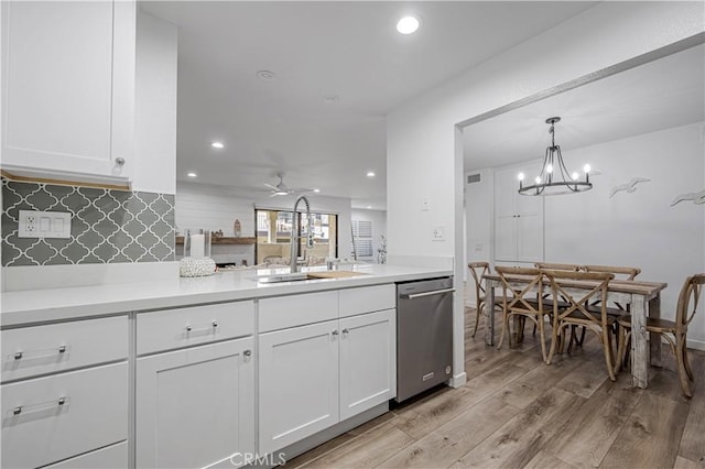 kitchen featuring light wood finished floors, tasteful backsplash, white cabinets, stainless steel dishwasher, and a sink