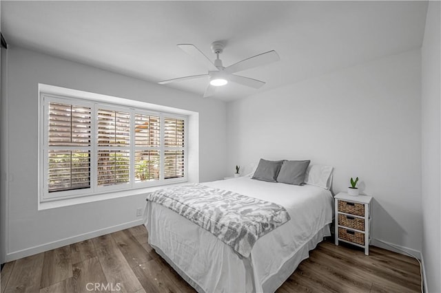 bedroom featuring ceiling fan, baseboards, and wood finished floors