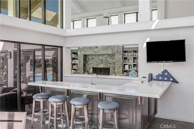 bar with a textured wall, a high ceiling, and indoor wet bar