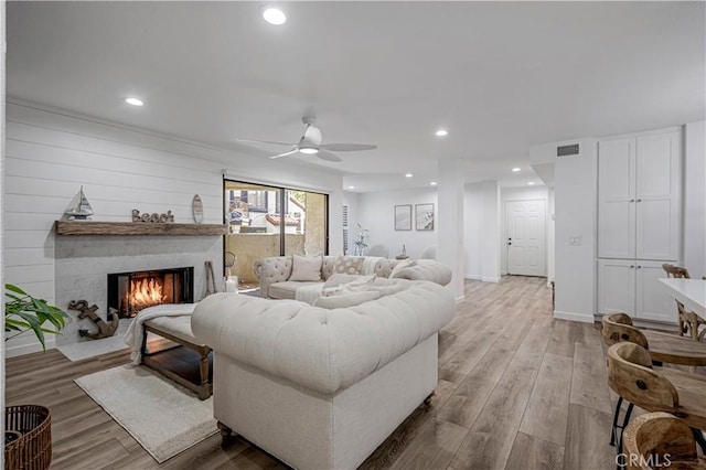 living room with a lit fireplace, visible vents, wood finished floors, and recessed lighting