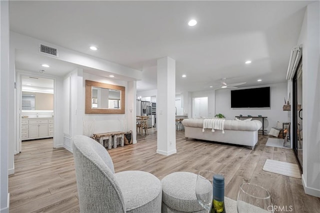 living room with light wood-type flooring, visible vents, and recessed lighting