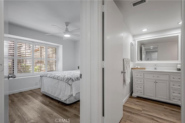 bedroom featuring a sink, baseboards, visible vents, and wood finished floors