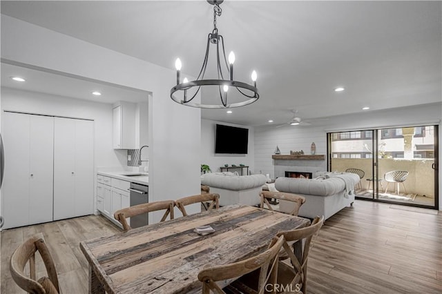 dining room with light wood-type flooring, ceiling fan, a fireplace, and recessed lighting