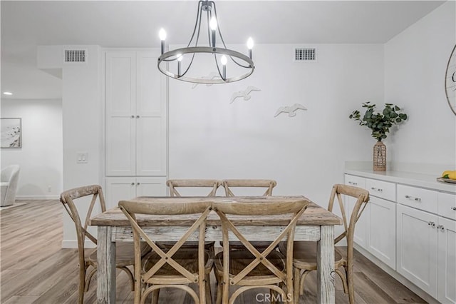 dining space with a chandelier, light wood-style flooring, and visible vents