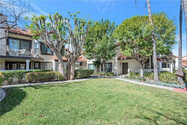 view of front facade featuring a front yard, a tiled roof, and stucco siding