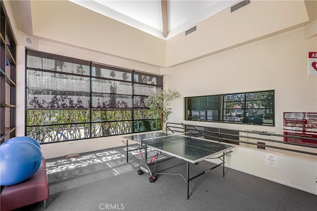 recreation room featuring visible vents and a high ceiling