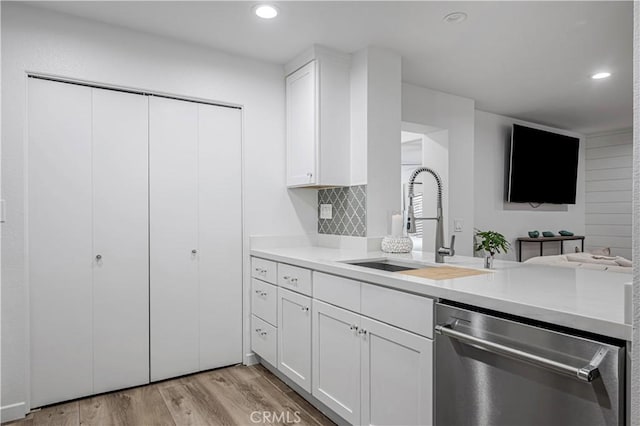 kitchen with dishwasher, light countertops, light wood-style floors, white cabinetry, and a sink