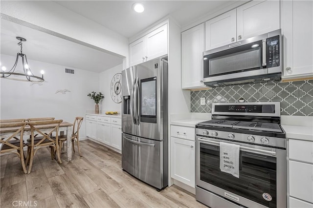 kitchen with stainless steel appliances, white cabinets, light wood finished floors, light countertops, and tasteful backsplash