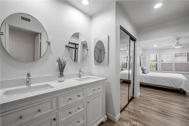 full bath featuring connected bathroom, a ceiling fan, a sink, and wood finished floors