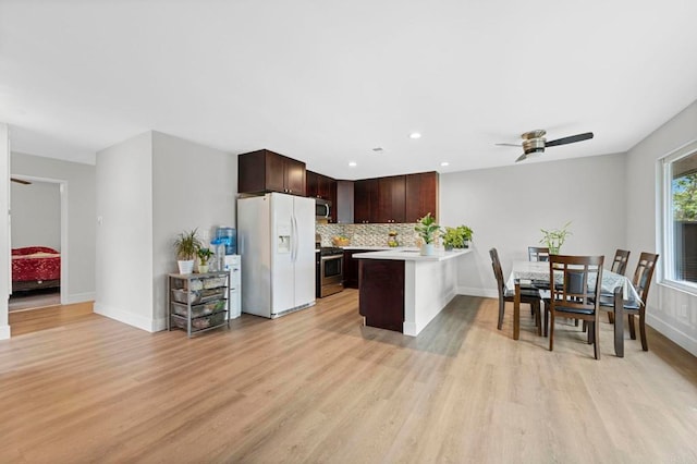 kitchen featuring dark brown cabinets, light countertops, decorative backsplash, light wood-style flooring, and stainless steel appliances