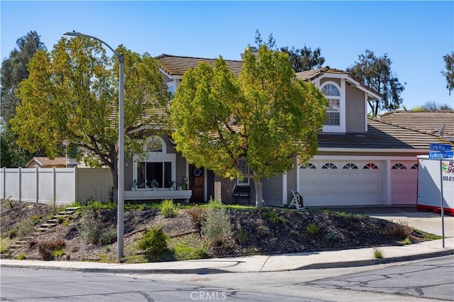 obstructed view of property featuring driveway, a tile roof, an attached garage, and fence