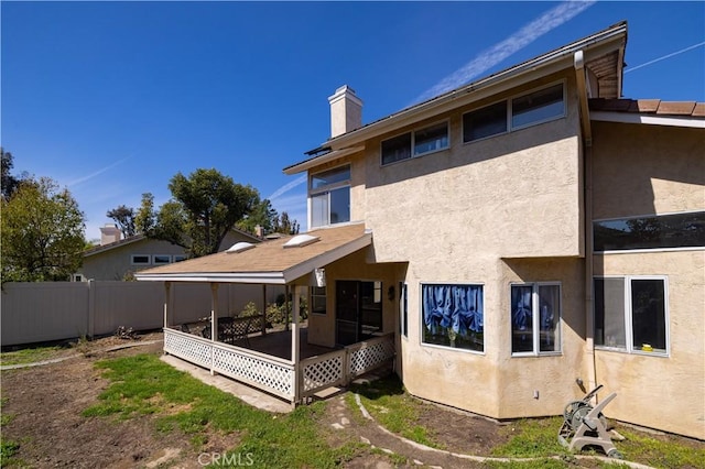 rear view of house featuring fence, a chimney, a sunroom, and stucco siding