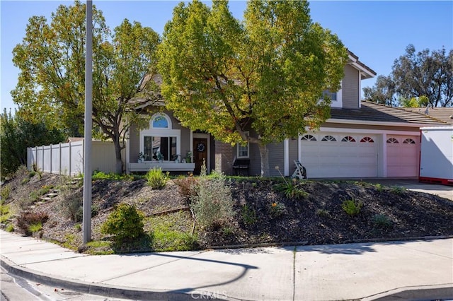 obstructed view of property featuring driveway, an attached garage, and fence