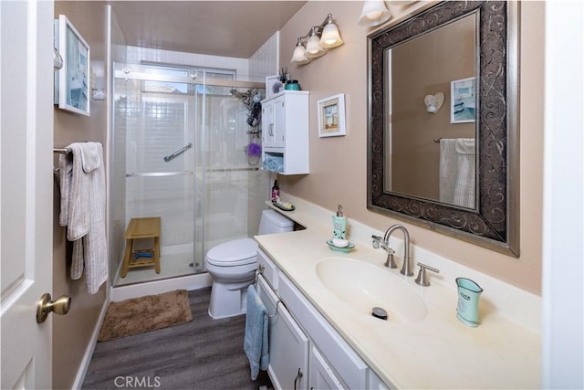 bathroom with vanity, a shower stall, toilet, and wood finished floors