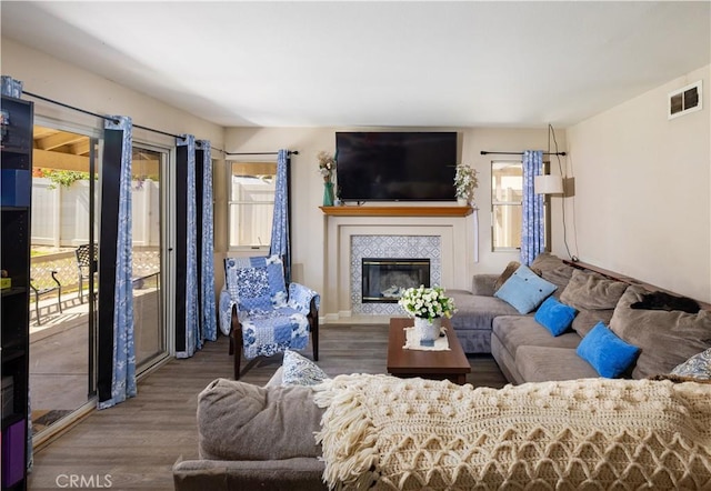 living room with a tiled fireplace, wood finished floors, and visible vents