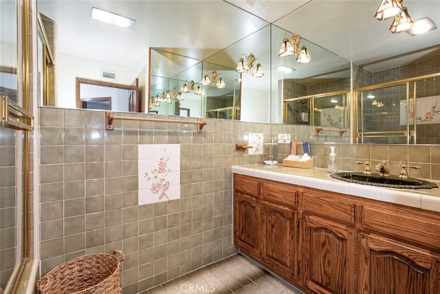 full bathroom with tile walls, visible vents, vanity, tile patterned flooring, and tiled shower