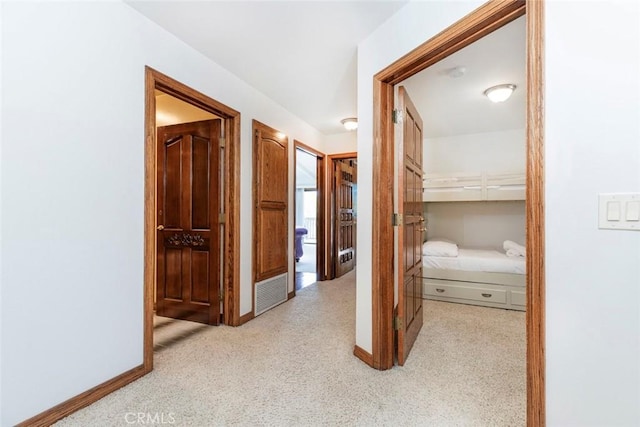 hall featuring baseboards, visible vents, and carpet flooring