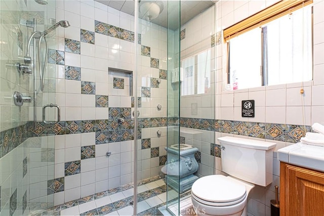 bathroom featuring toilet, vanity, a shower stall, and tile walls