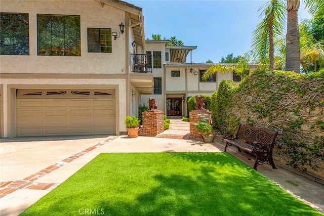 view of front of property with a balcony, an attached garage, a front yard, and stucco siding