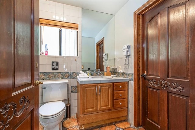 half bath with toilet, vanity, and tile walls