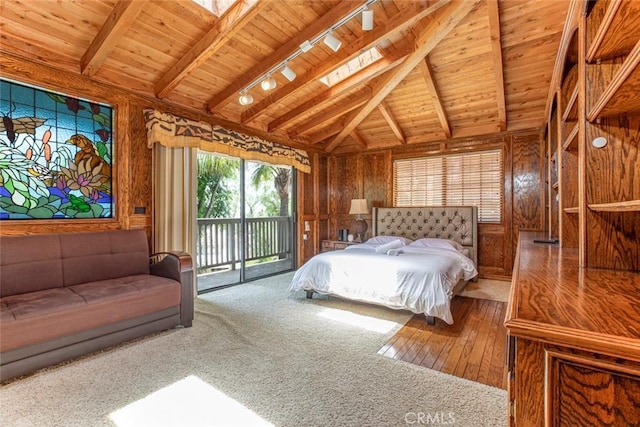 bedroom with wood walls, wood ceiling, access to outside, lofted ceiling with skylight, and track lighting