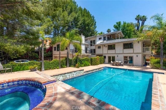 view of swimming pool featuring a pool with connected hot tub and a patio