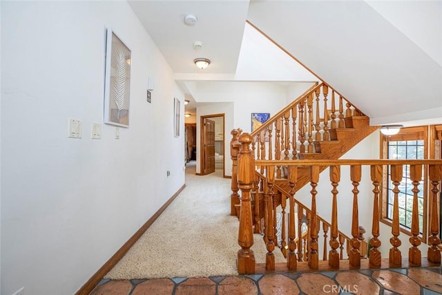 hallway featuring vaulted ceiling, stairway, carpet flooring, and baseboards