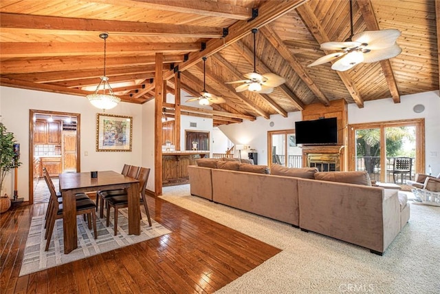 living room featuring high vaulted ceiling, hardwood / wood-style flooring, a large fireplace, wood ceiling, and beam ceiling