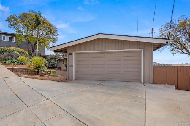 garage featuring fence and concrete driveway