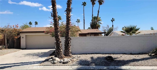 view of front of property with concrete driveway, an attached garage, and fence