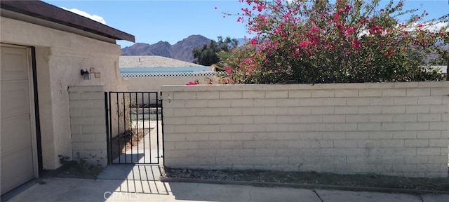 view of gate with fence and a mountain view