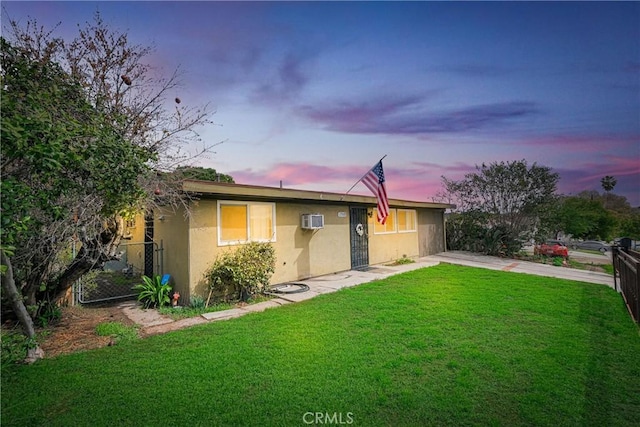 view of front of property with stucco siding, a wall mounted AC, a front yard, a gate, and fence