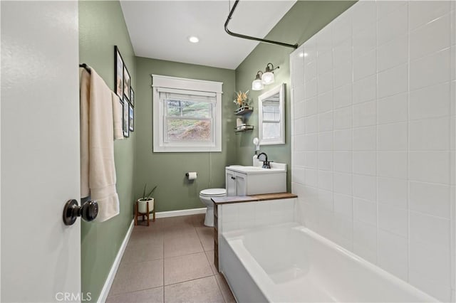 bathroom with tile patterned floors, toilet, baseboards, and a sink