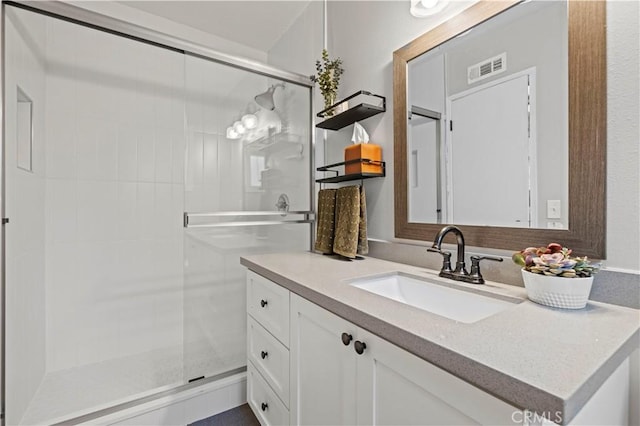 full bath with vanity, a shower stall, and visible vents