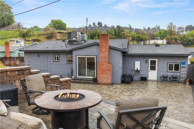 back of property featuring stucco siding, a patio, a fire pit, and fence