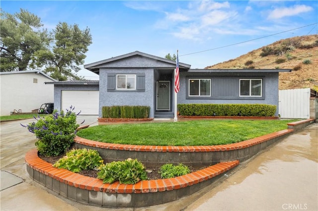 ranch-style house featuring a front lawn, fence, driveway, and stucco siding