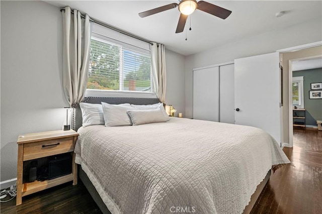 bedroom with a ceiling fan, wood finished floors, baseboards, and a closet