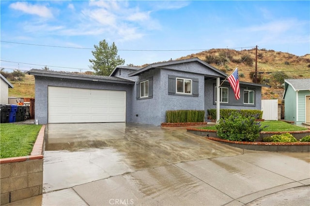 ranch-style house with stucco siding, driveway, a front yard, and a garage