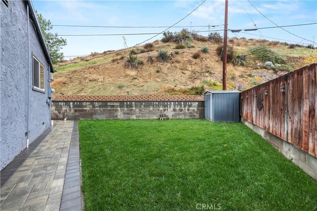 view of yard featuring an outdoor structure, a fenced backyard, and a shed