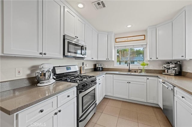 kitchen with visible vents, light tile patterned floors, white cabinets, stainless steel appliances, and a sink